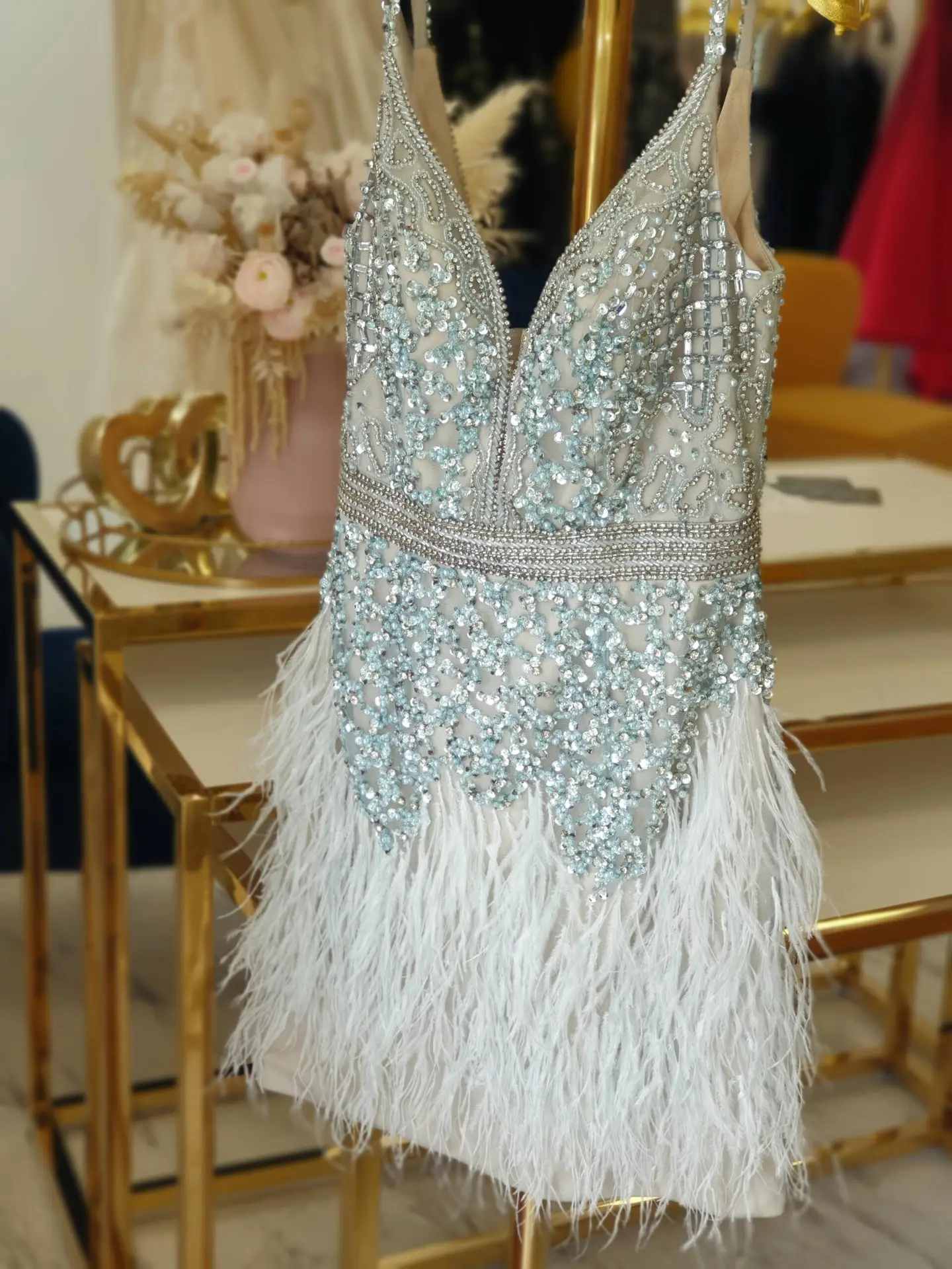 Short cocktail dress with rhinestones and white feathers on a hanger
